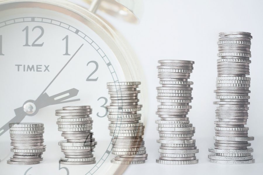 clock faded with stacks of coins in front of it